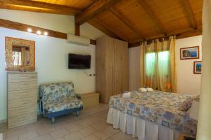 a bedroom with a bed and a chair and a television at Elbaloves Appartaments Villa in Capoliveri