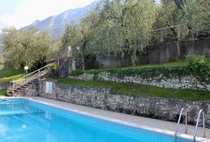 a large swimming pool with a stone wall and stairs at Appartamento Venzo in Brenzone sul Garda