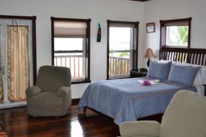a bedroom with a bed and a chair and windows at Belizean Nirvana in Placencia Village +69 photos