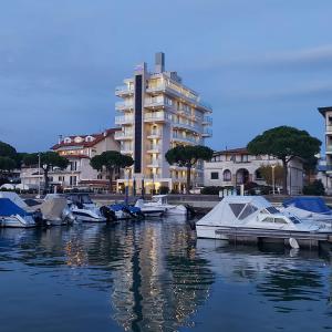 un groupe de bateaux amarrés dans un port avec un bâtiment dans l'établissement Hotel Mare, à Lignano Sabbiadoro