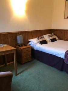 two beds in a room with a desk and a chair at The Banks Of Ury in Inverurie