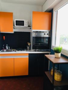 a kitchen with orange cabinets and a microwave at Bleu Salé - F2 Courseulles avec balcon in Courseulles-sur-Mer +23 photos