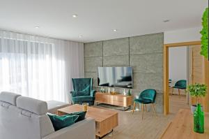 een woonkamer met een bank en stoelen en een tv bij Apartament Na Borach I SPA in Szczyrk