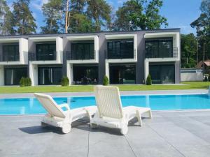 two white chairs sitting next to a swimming pool at Aprum Apartments 10C in Pobierowo