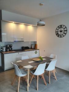 cocina con mesa, sillas y reloj en Aprum Apartments 10C en Pobierowo