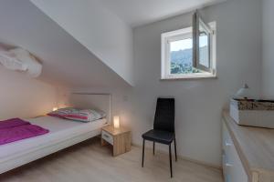 a bedroom with a bed and a window and a chair at Apartment Karin in Veli Lošinj