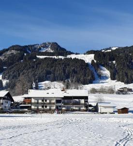 ein Gebäude im Schnee vor einem Berg in der Unterkunft Bergkristall - Freie Fahrt Allgäuer Hörnerbahnen im Sommer in Bolsterlang