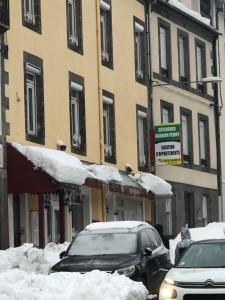 twee auto's geparkeerd op een straat bedekt met sneeuw bij Résidence Bardon-Perry in Le Mont-Dore