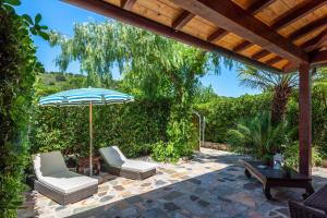a patio with two chairs and an umbrella at Elbaloves Appartaments Villa in Capoliveri
