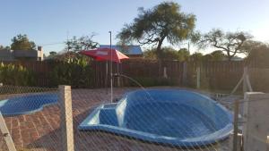 a swimming pool with an umbrella next to a fence at Cabañas Diamante in Gualeguaychú