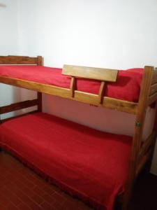 圣贝尔纳多Duplex en San Bernardo a dos cuadras de la playa的红色床单的客房内的两张双层床