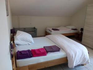 Dos camas en una habitación con toallas. en La Maison Jaune en Cleurie