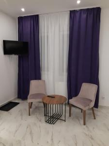 2 sillas y una mesa en una habitación con cortinas moradas en Villa Anela en Pasuljište