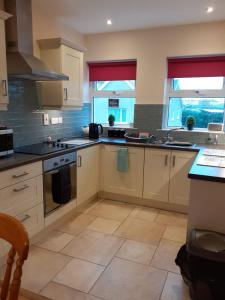 a kitchen with white cabinets and counters and two windows at Beachside Holiday Home in Portrush
