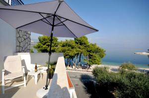 eine Terrasse mit einem Sonnenschirm, Stühlen und Meerblick in der Unterkunft Apartments Penić in Trogir