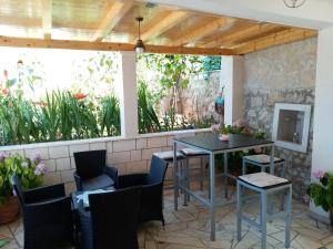 eine Terrasse mit einem Tisch, Stühlen und einer Steinmauer in der Unterkunft Apartment Ivan & Kate in Dubrovnik