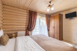 Schlafzimmer mit einem Bett, einem TV und einem Fenster in der Unterkunft Guest House Turda in Bukowel