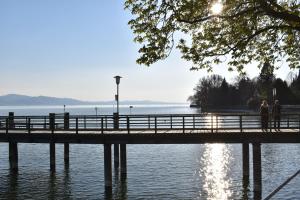 two people walking on a pier over the water at Hotel Lindenallee in Lindau