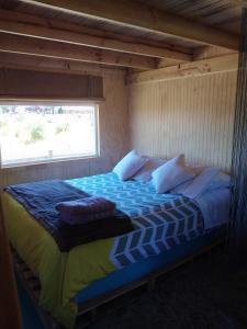 a large bed in a room with a window at Fío Fío Patagonia in Chaitén