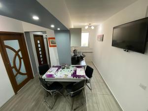 a dining room with a table with chairs and a flat screen tv at Apartament Sulina in Sulina