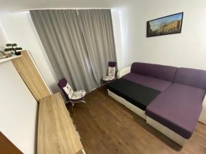 a bedroom with a purple bed and two chairs at Apartament Sulina in Sulina