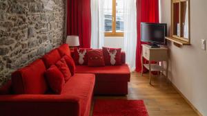 sala de estar con sofá rojo y TV en L'ancienne Poste - Maison Napoléon, en Bourg-Saint-Pierre