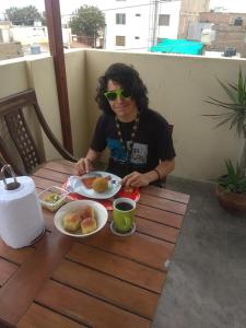 una mujer sentada en una mesa con un plato de comida en Lola Hosting en Huanchaco