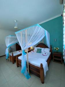 a bedroom with two beds with a canopy at Pumzika Kendwa Villa in Kendwa