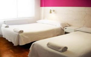 a room with two beds with white sheets at Pensión Boreal Solano in Burgos