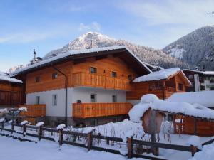duży drewniany dom z śniegiem na dachu w obiekcie Ciasa Giorgina w mieście Pozza di Fassa