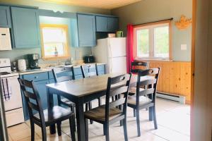 a kitchen with a table and chairs and a refrigerator at lovely chalet near the beach in Pointe-du-Chêne