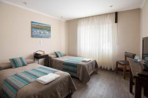 um quarto de hotel com duas camas e uma secretária em Hotel Amado em El Calafate