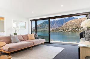 a living room with a couch and a large window at 'LakeLife' Lake Front Apartment in Queenstown