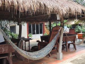 a hammock and a table and chairs under a straw umbrella at Meas Family Homestay in Angk Ta Saom