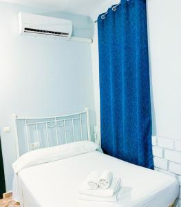 1 dormitorio con 1 cama con cortina azul en El Castillo, en Alcalá de Guadaira