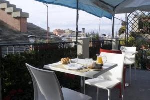 un tavolo bianco e sedie su un balcone con ombrellone di Hotel Colombo Genova a Genova