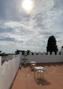 un patio con 2 mesas y una valla blanca en El Castillo, en Alcalá de Guadaira