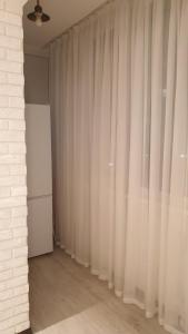 um quarto com cortinas brancas numa parede em Сдам ПОСУТОЧНО уютную квартиру на Марсельской em Kryzhanivka