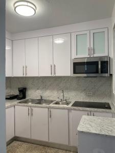 uma cozinha com armários brancos, um lavatório e um micro-ondas em San Juan Home em San Juan