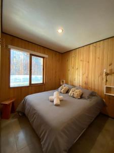 1 dormitorio con 1 cama grande y ventana en Cabañas Koyam Ruka, en Licán Ray