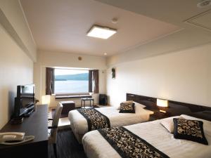 Habitación de hotel con 2 camas y ventana en Akan No Mori Tsuruga Resort Hanayuuka, en Akankohan