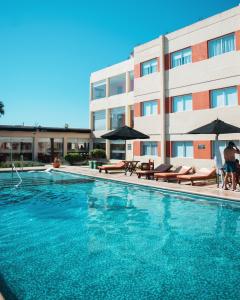 - une piscine avec des chaises et des parasols en face d'un bâtiment dans l'établissement Hotel Termal Los Cardones & Spa, à Termas de Río Hondo