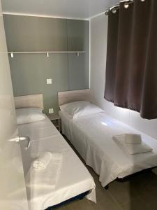 - 2 lits dans une petite chambre avec fenêtre dans l'établissement Palombaggia location i pini Porto Vecchio, à Porto-Vecchio