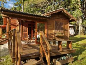 a wooden cabin with a deck and a table at Refúgio da Pedra - Casa na Montanha, Gonçalves-MG in Gonçalves