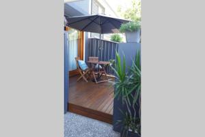 a wooden deck with an umbrella and a table at Woolloongabba, comfortable, modern, private studio in Brisbane