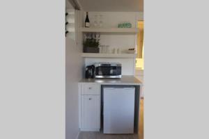 a kitchen with white cabinets and a microwave at Woolloongabba, comfortable, modern, private studio in Brisbane