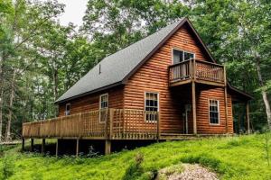 eine Blockhütte im Wald mit Balkon in der Unterkunft Remote Cabin WV Retreat-Escape from the Norm in Mathias