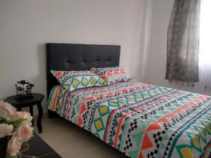 een slaapkamer met een bed met een kleurrijk dekbed bij Familia Lombana in Bogota