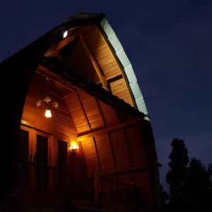 eine große Holzhütte mit einem Bogenfenster in der Nacht in der Unterkunft Villa Lumbung Salak in Bogor