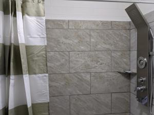 a shower with a stone wall and a shower curtain at Belle Aire Motel in Globe